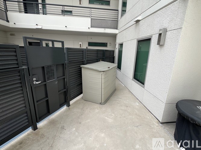 A storage unit sits in the corner of a concrete courtyard between two buildings.