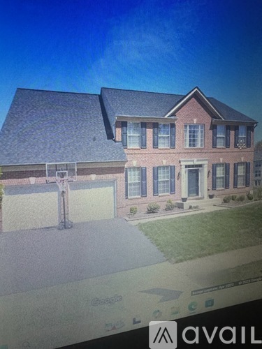 A large red brick house with a driveway in front.