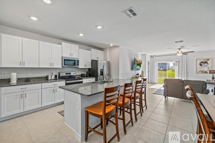 A kitchen with white cabinets and a marble countertop.