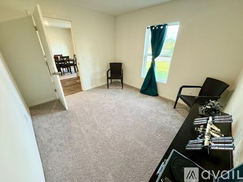 A living room with a black chair and a table with a few items on it.