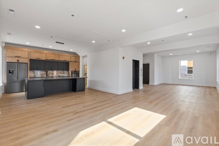 A spacious living room with a kitchen area in the background.