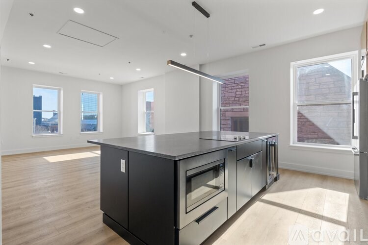 A modern kitchen with black cabinets and stainless steel appliances.