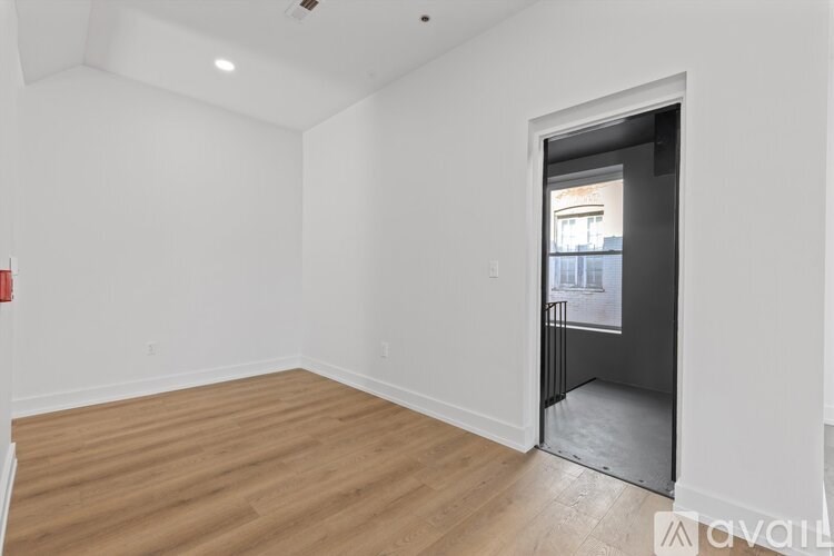 A room with wooden flooring and a doorway leading to another room.