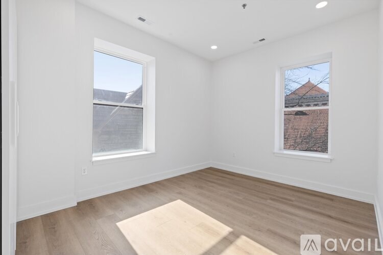 A room with a window and a view of a house across the way.