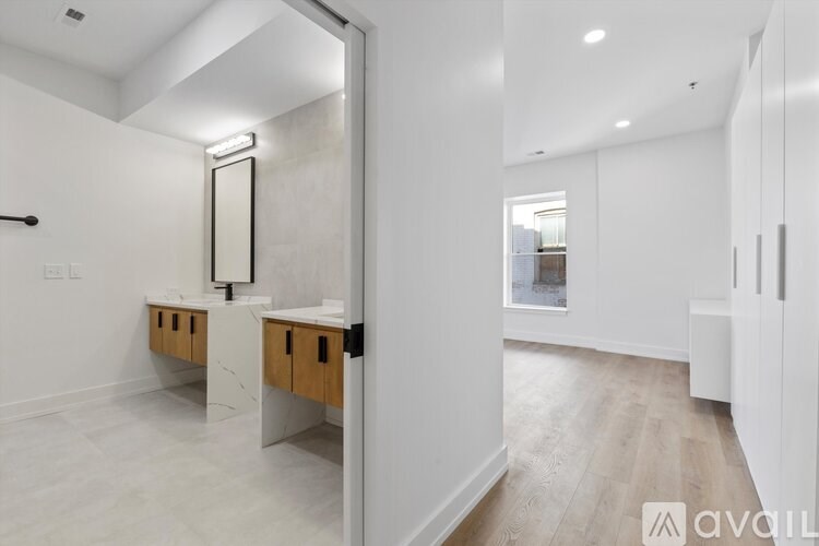 A bathroom with a sink and mirror in a white room.