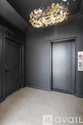 A room with two doors and a chandelier hanging from the ceiling.