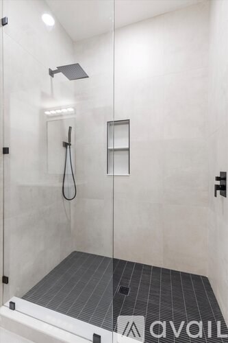 A shower area with a glass door and a black tiled floor.