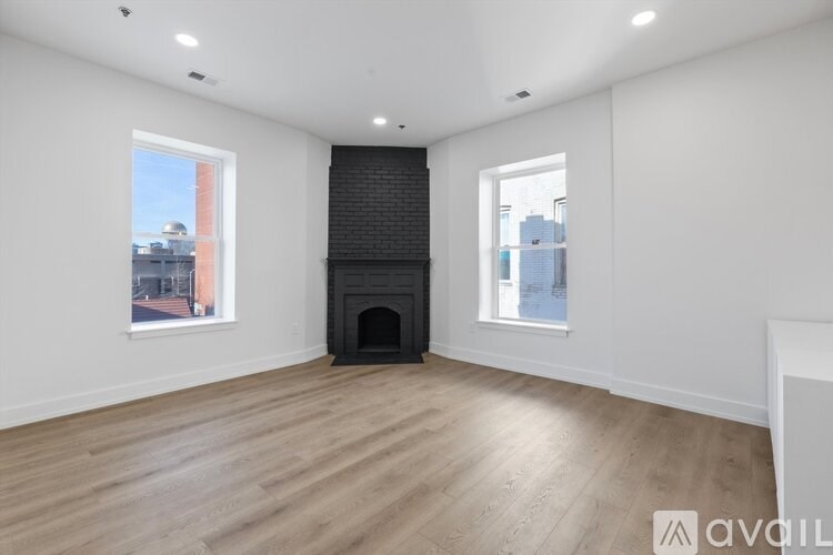A spacious room with a fireplace and two windows.