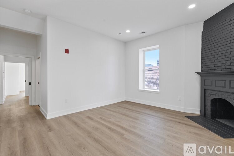 A spacious room with a fireplace and a window overlooking a cityscape.