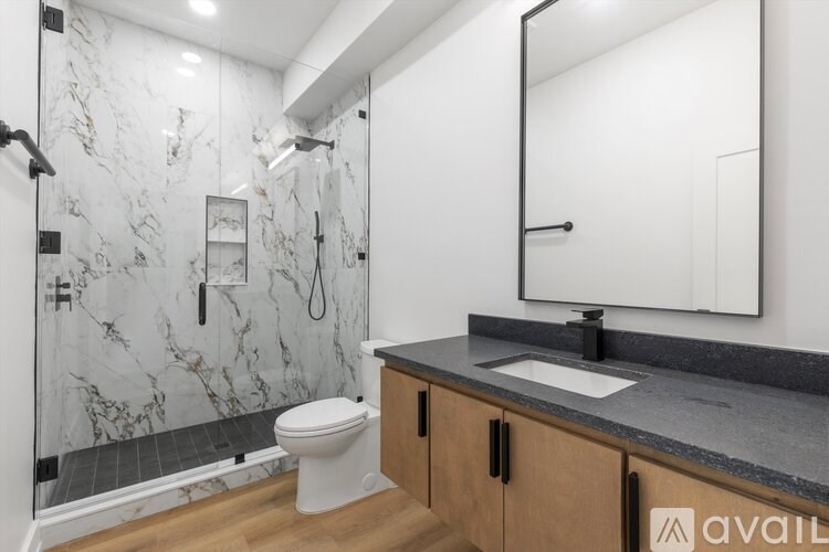 A bathroom with a marble shower and a white toilet.