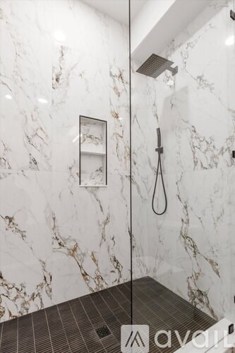 A marble bathroom with a shower head and a glass door.