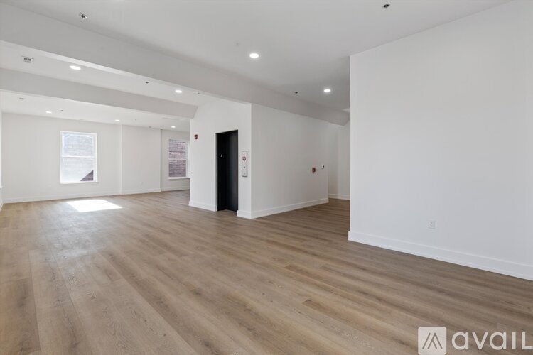 A spacious room with wooden flooring and white walls.