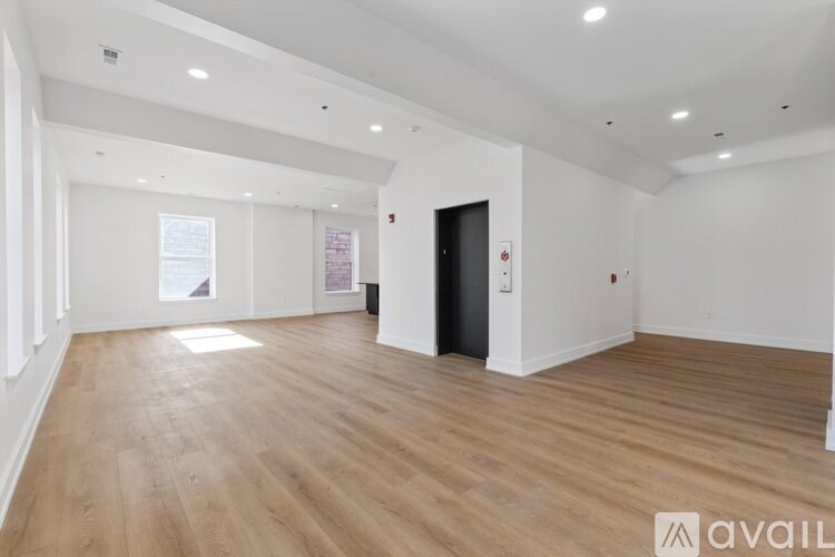 A spacious room with wooden flooring and white walls.