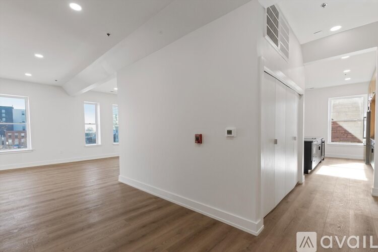 A spacious, empty room with wooden floors and white walls.