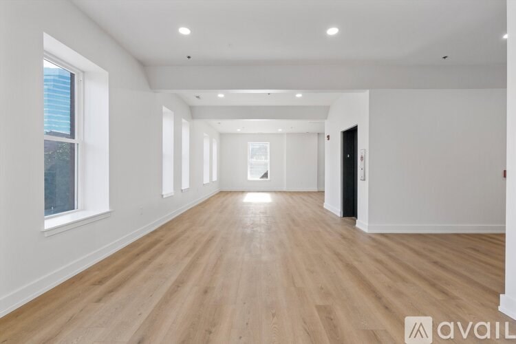A spacious room with wooden flooring and white walls.