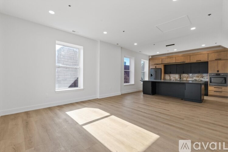 A spacious living room with a kitchen area in the background.