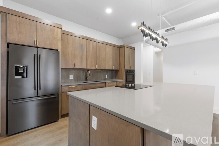 A kitchen with a stainless steel refrigerator and wooden cabinets.