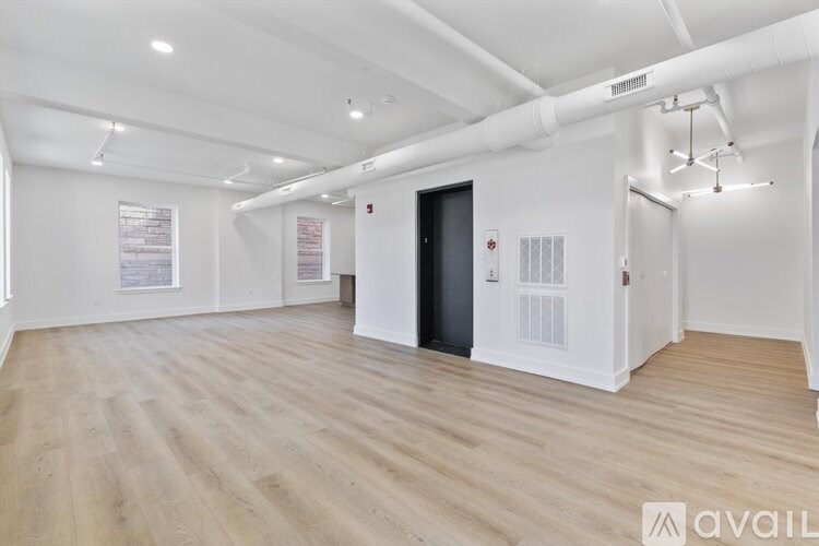 A spacious room with wooden flooring and white walls.
