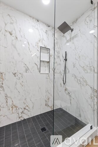 A bathroom with a marble wall and a glass shower door.