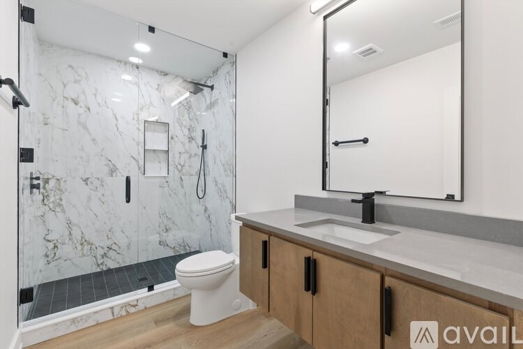 A bathroom with a marble shower and a white toilet.