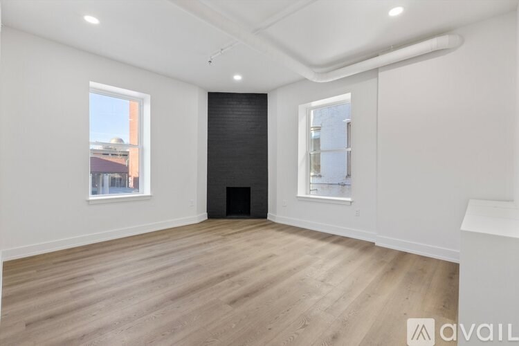 A spacious room with wooden flooring and white walls.