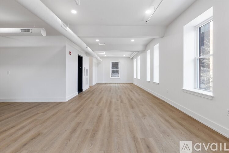 A spacious room with wooden flooring and white walls.
