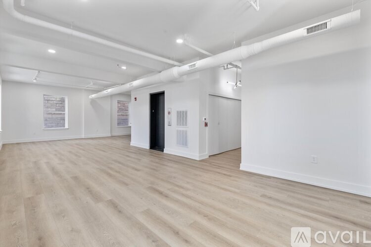 A spacious room with wooden flooring and white walls.