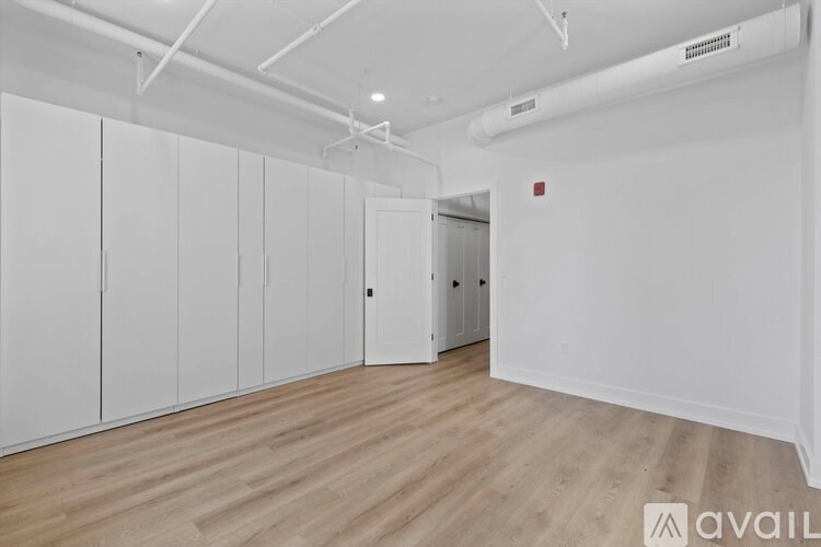 A spacious room with wooden flooring and white walls.