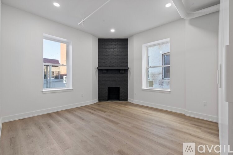 A spacious room with wooden flooring and a fireplace.