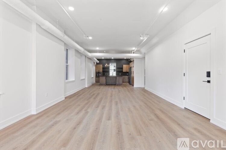 A long, empty hallway with wooden floors and white walls.