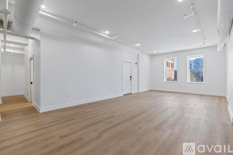 A spacious room with wooden flooring and white walls.