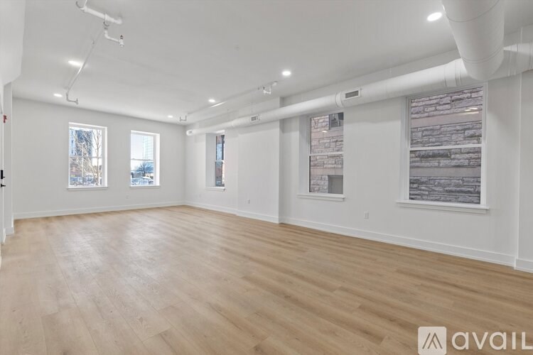 A spacious room with wooden flooring and white walls.