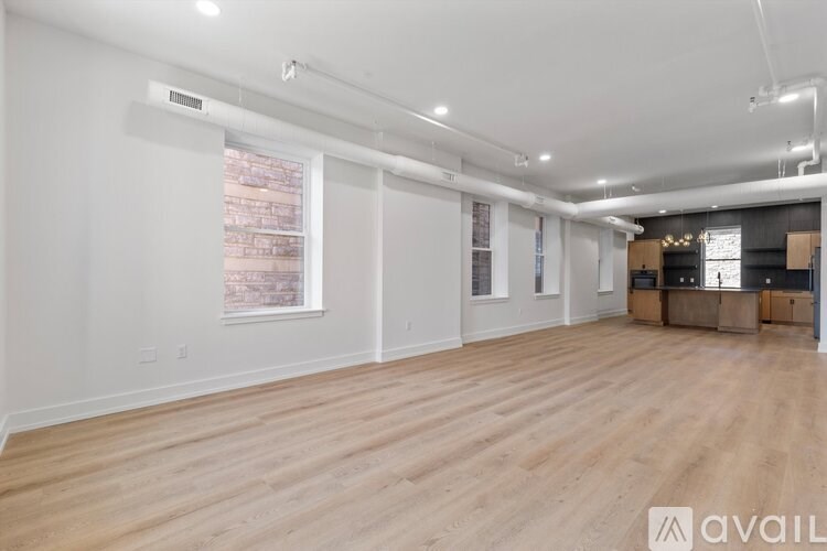 A spacious room with wooden flooring and white walls.