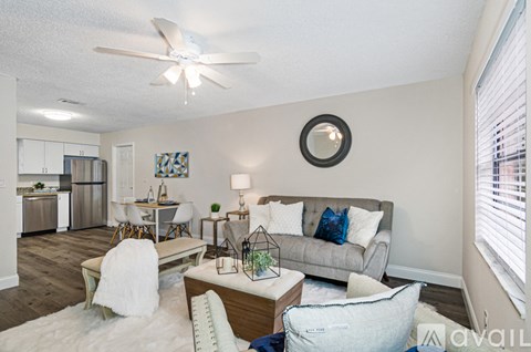 A living room with a grey couch and a white rug.