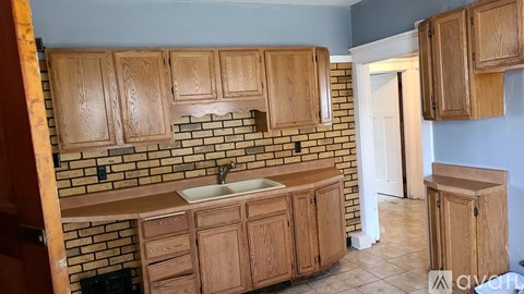 A kitchen with wooden cabinets and a brick backsplash.