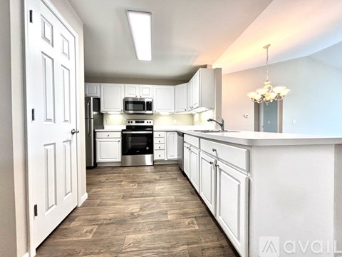 A kitchen with white cabinets and a wooden floor.