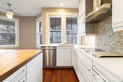A kitchen with white cabinets and a wooden counter top.