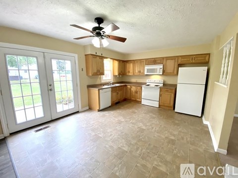 A kitchen with a fan on the ceiling and a refrigerator on the right side.