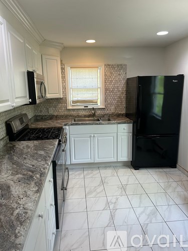 A kitchen with black appliances and white cabinets.