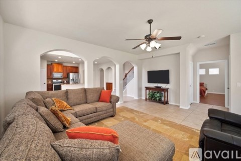 A living room with a grey couch and a ceiling fan.