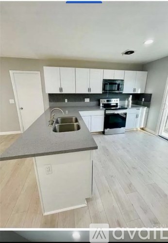 A kitchen with white cabinets and a grey countertop.