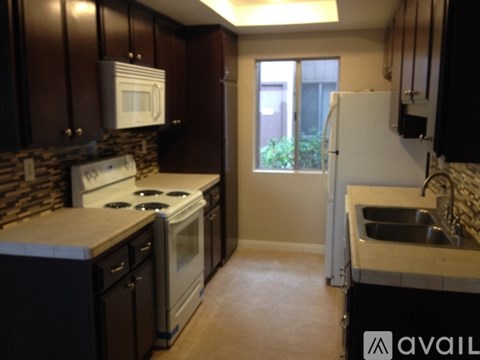 A kitchen with dark wood cabinets and white appliances.