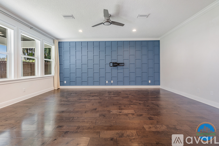 A spacious room with a wooden floor and a ceiling fan.