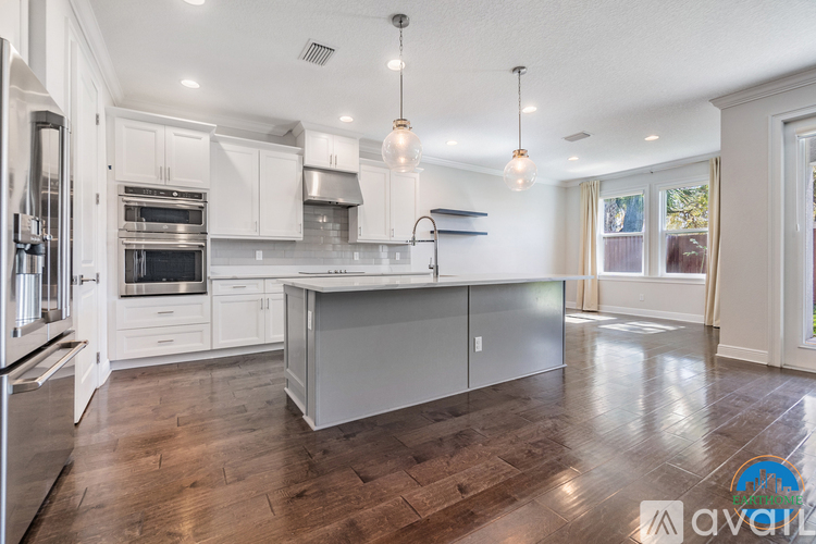 A modern kitchen with white cabinets and a wooden floor.