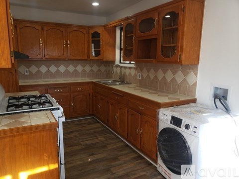 A kitchen with wooden cabinets and a washing machine on the counter.