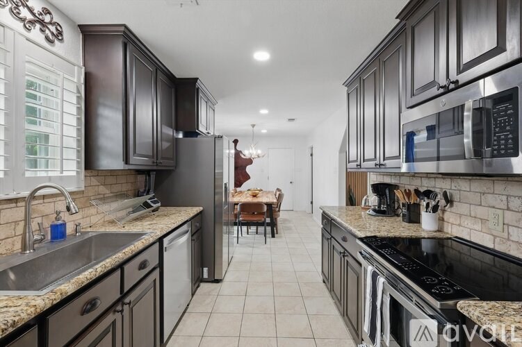 A kitchen with dark brown cabinets and a black stove top oven.