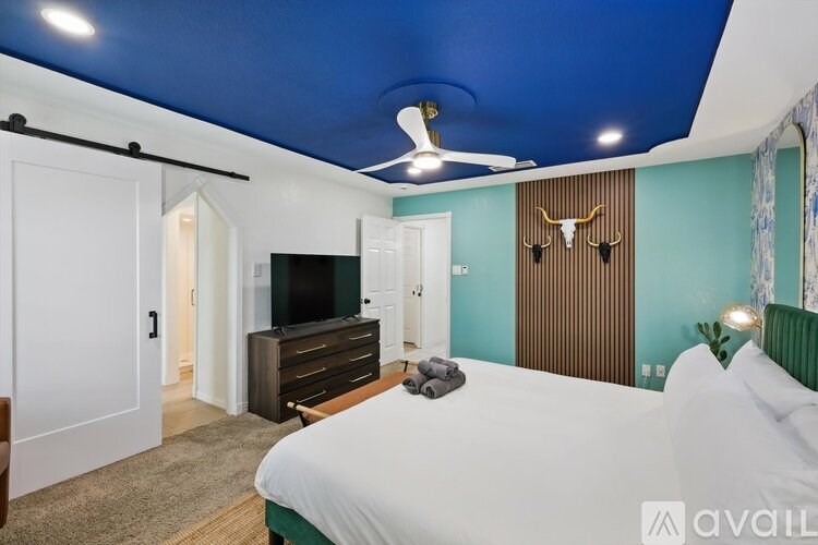 A bedroom with a bed, dresser, and a ceiling fan.