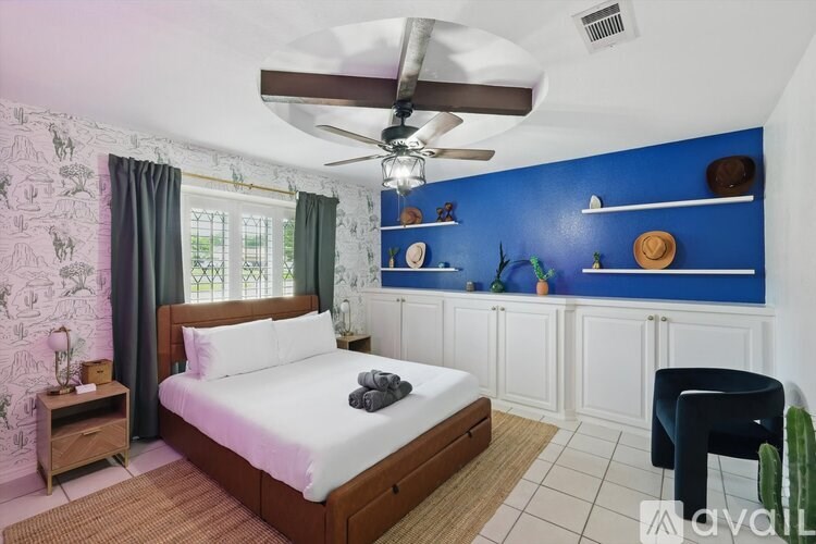 A bedroom with a bed, a ceiling fan, and a window with curtains.