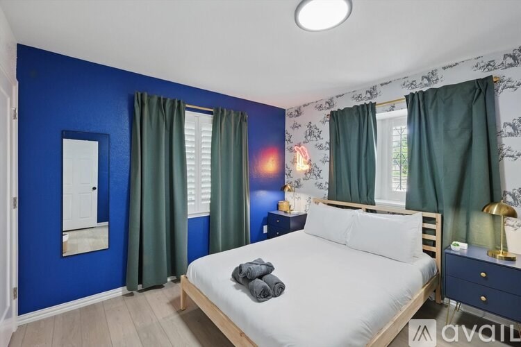 A bedroom with blue walls and a white bed.