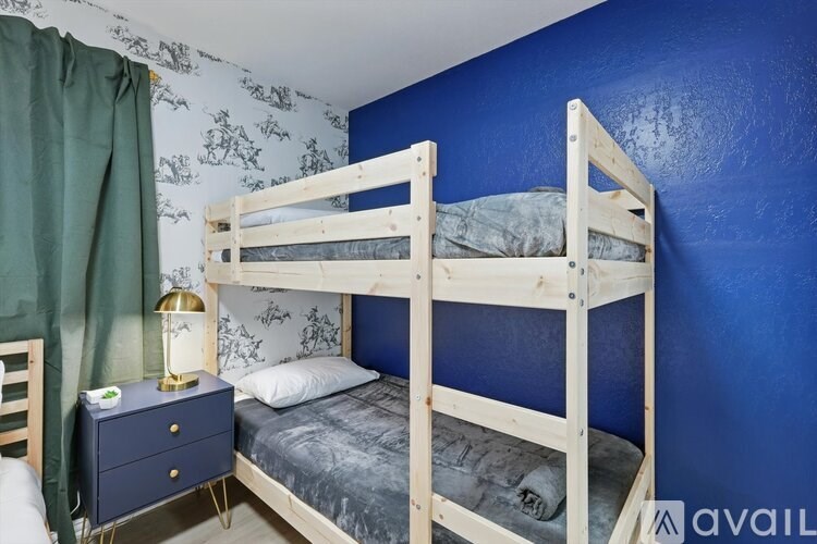 A bunk bed in a room with blue walls and a green curtain.